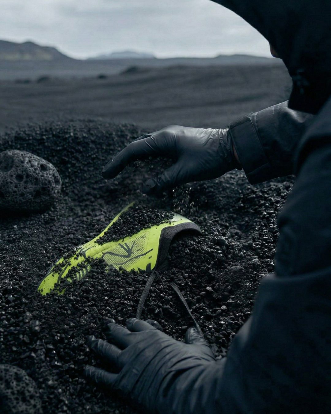 Mains gantées dégageant la chaussure du sable noir